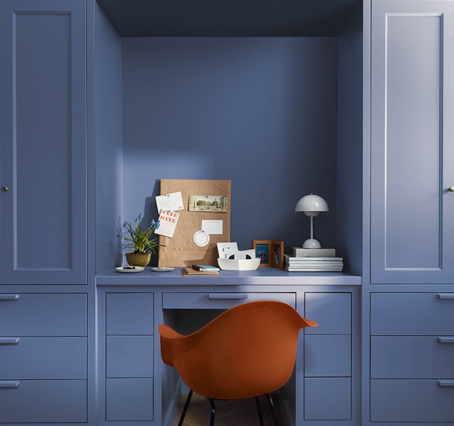 A dressing table and wardrobes painted in Blue Nova 835. Alongside is a burnt orange chair and decorative accessories