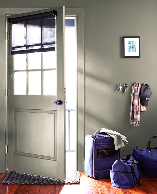 An entrywall colour-drenched in Antique Pewter 1560. Striking blue luggage and clothing accessories decorate the space