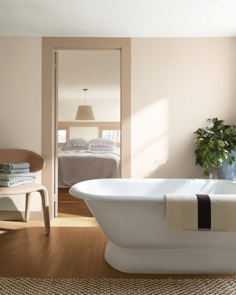 A bathroom with freestanding bath and view through to a bedroom. Walls are painted in First Crush CSP-310 and woodwork is painted in Sherwood Tan 1054.