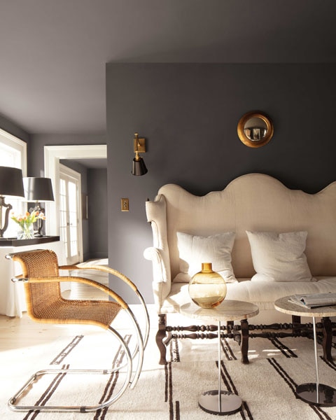 A living room space with a striking high backed scalloped sofa. The walls and ceilings are colour drenched in Silhouette AF-655 with contrasting woodwork in Swiss Coffee OC-45.