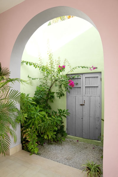 A courtyard featuring a rendered archway with walls painted in Aura Exterior Low Lustre in Marry Me 1290 and Veranda View 541