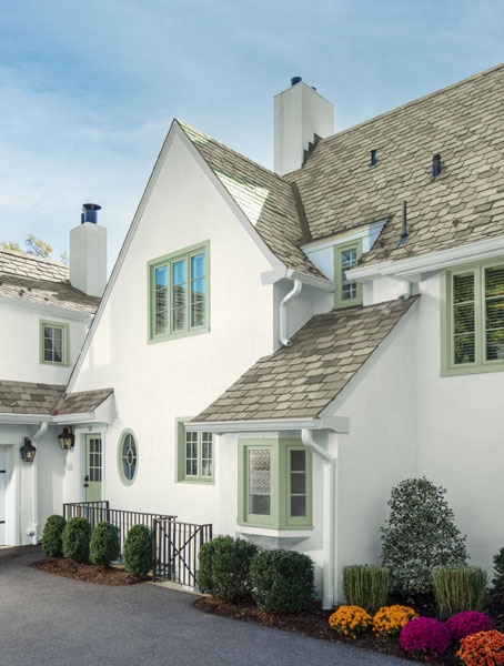 A two-storey home with slopping tiled roof. The window frames are door are painted in Aura Exterior Satin Salisbury Green HC-139 and the rendered walls are painted in Aura Exterior Low Lustre in Cloud White OC-130